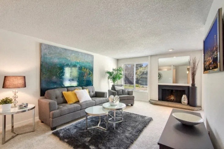 A living room with a grey couch, a coffee table, a fireplace, and a painting on the wall. at The Retreat, Washington, 98390