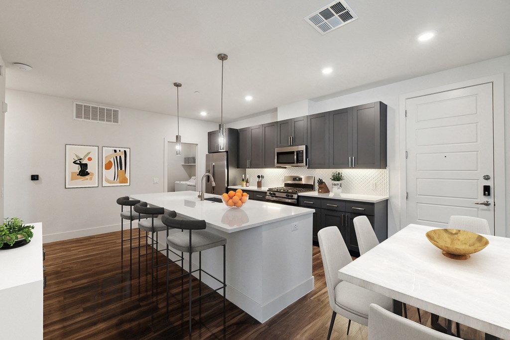 an open kitchen and dining room with white countertops and dark cabinets