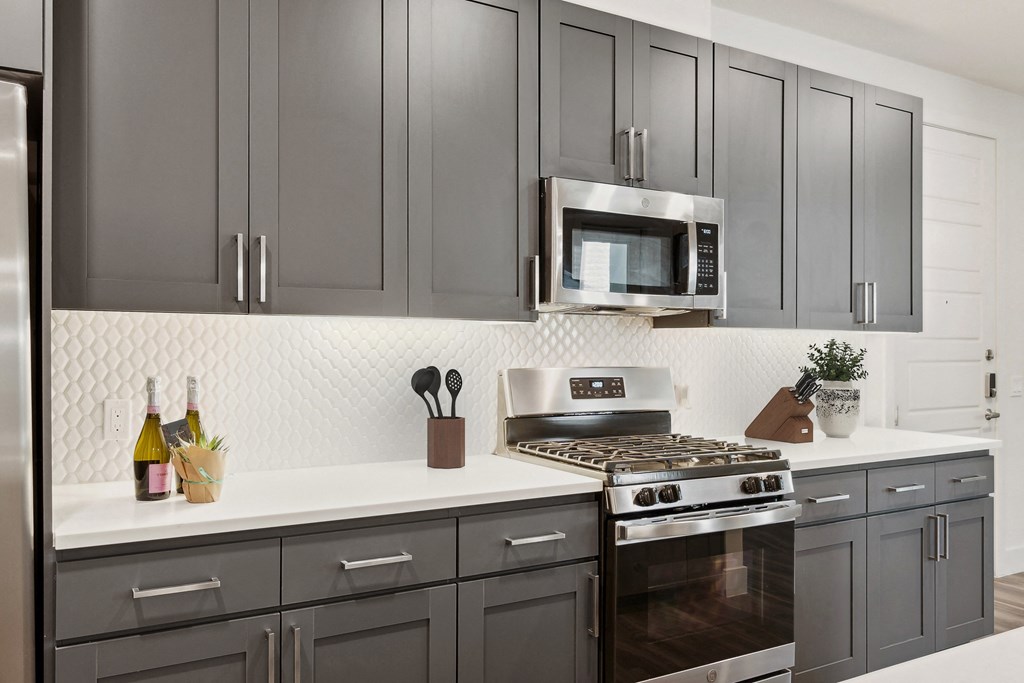 a kitchen with gray cabinets and a stove and a microwave