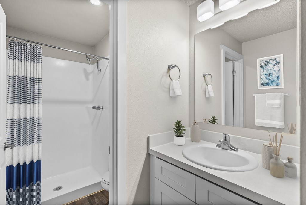 A bathroom with a white sink and a shower with a blue and white curtain.