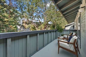 A wooden chair with a cushion is on a balcony.