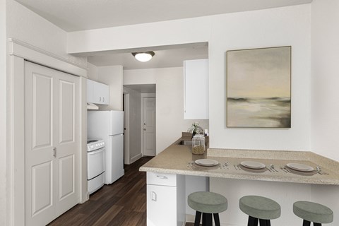 A kitchen with a table set for two with a painting hanging on the wall.