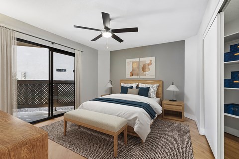 A bedroom with a bed, nightstand, and a ceiling fan.