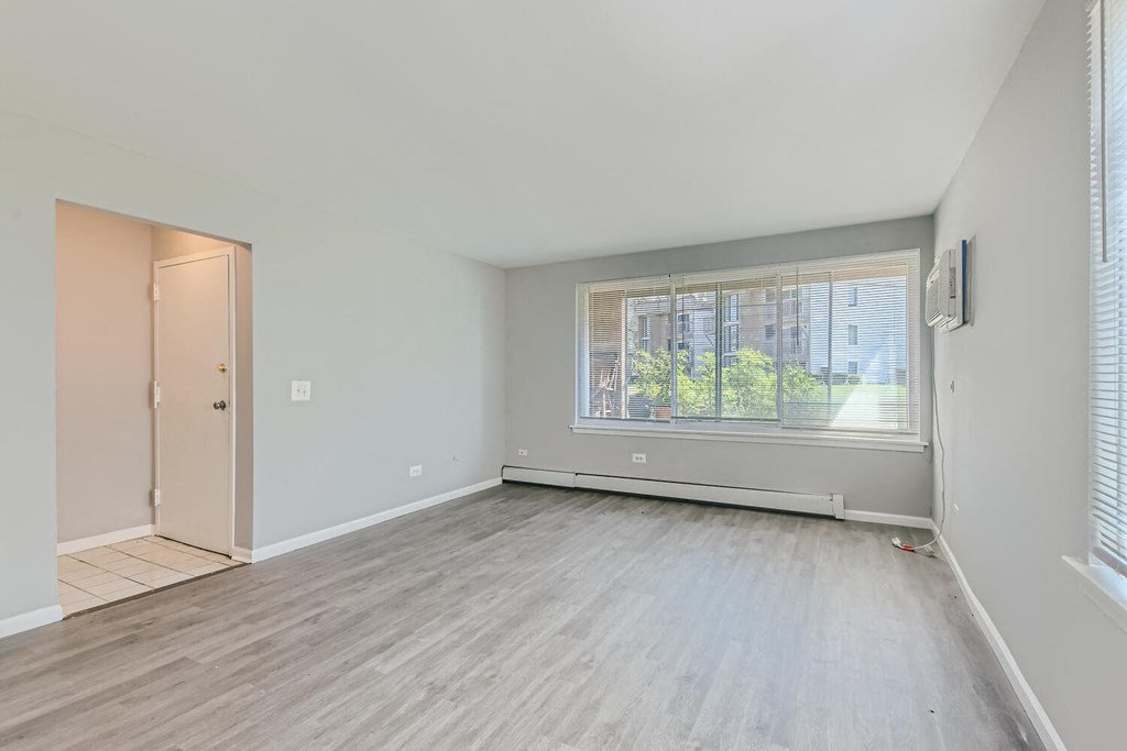 an empty living room with a large window and wood floors