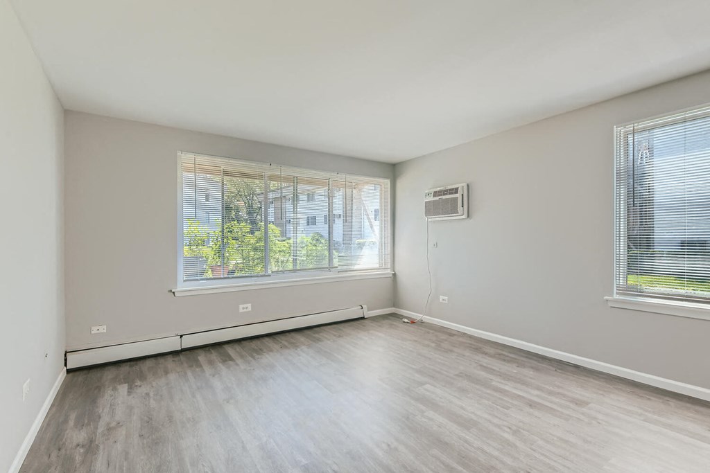 an empty living room with wood floors and two windows
