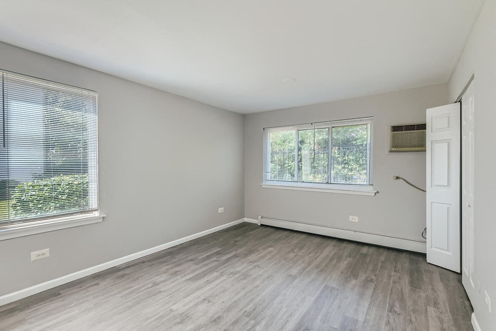 an empty bedroom with wood floors and a window