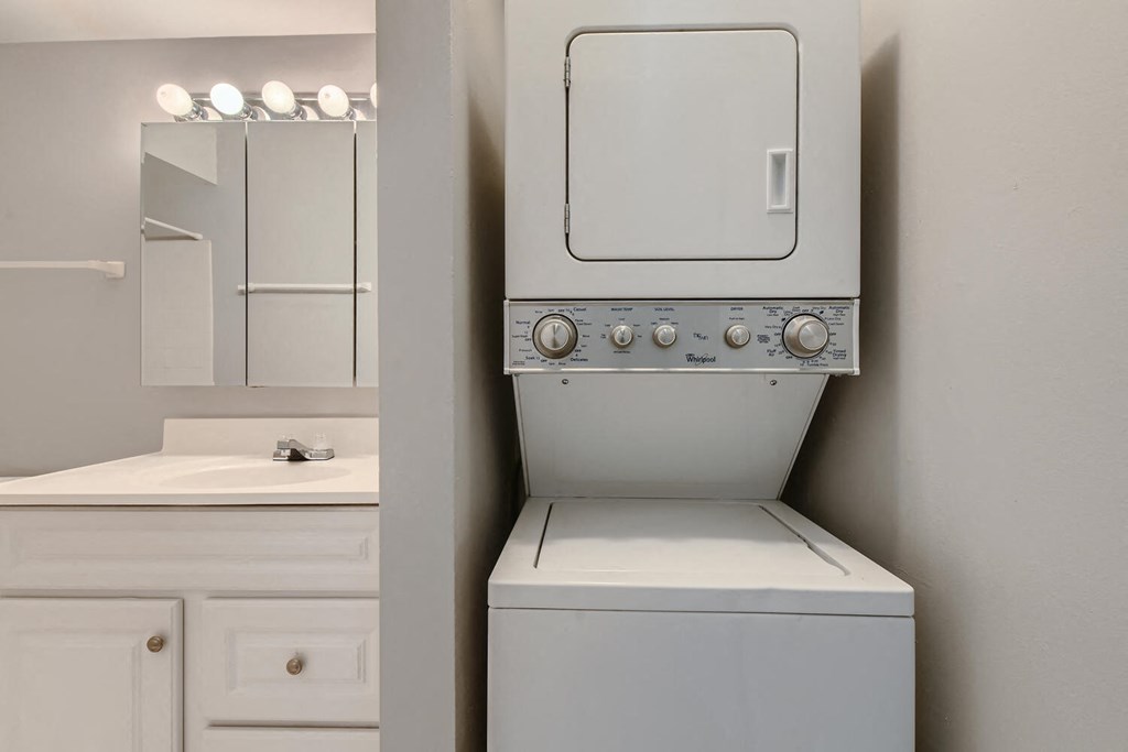 a white washer and dryer in a bathroom with a sink