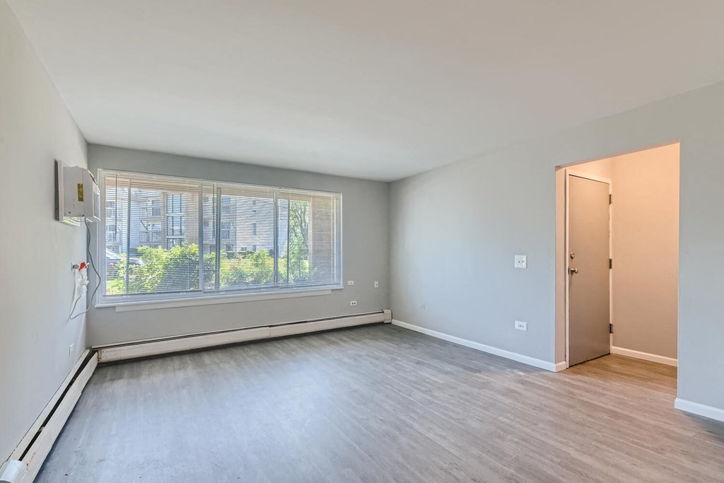 an empty living room with a large window and wooden floors