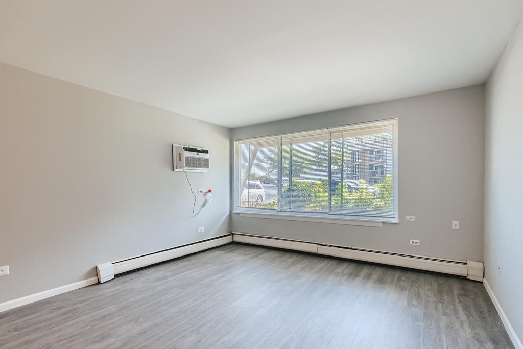 an empty living room with a large window and wood floors