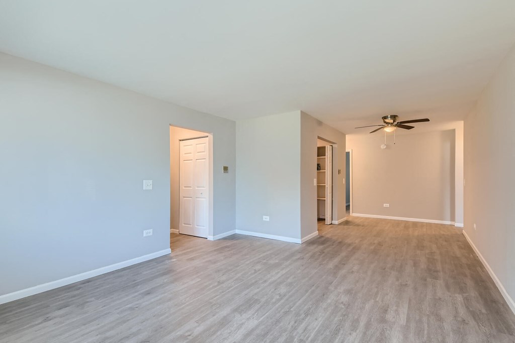 an empty living room with a ceiling fan and a wood floor