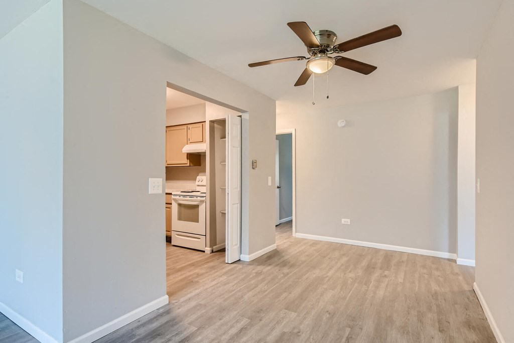 a renovated living room with a ceiling fan and a kitchen