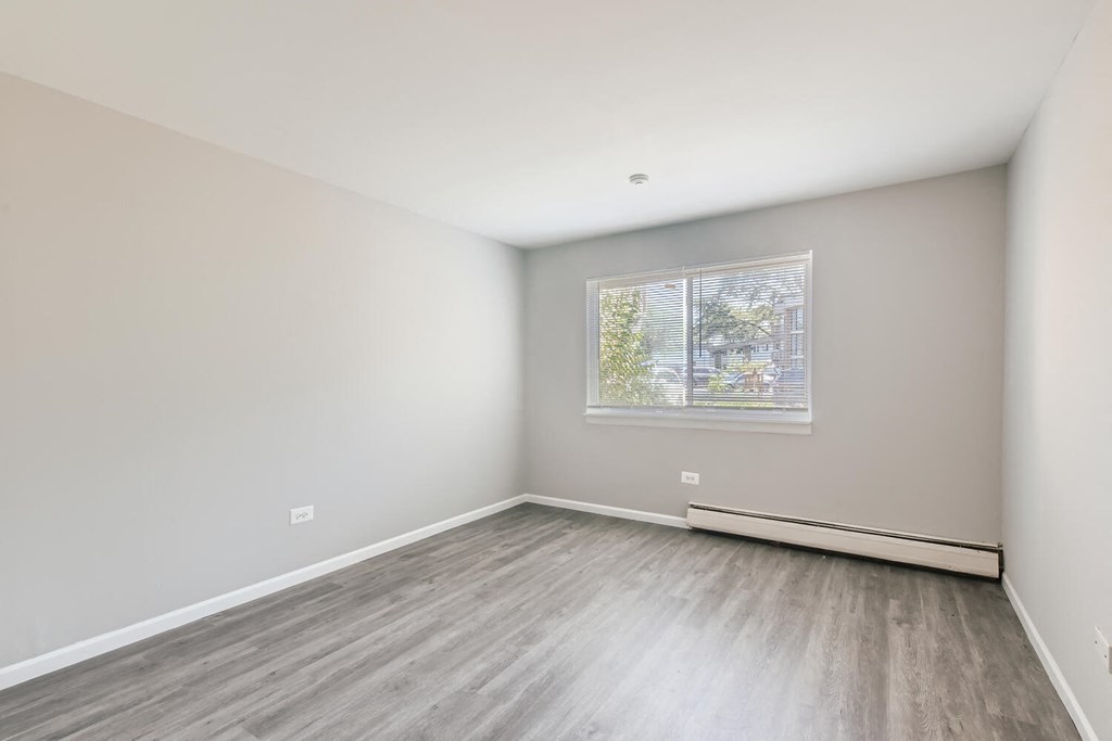 a bedroom with wood floors and white walls and a window