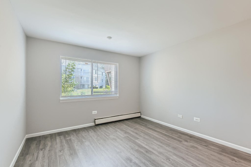 an empty room with wood floors and a window
