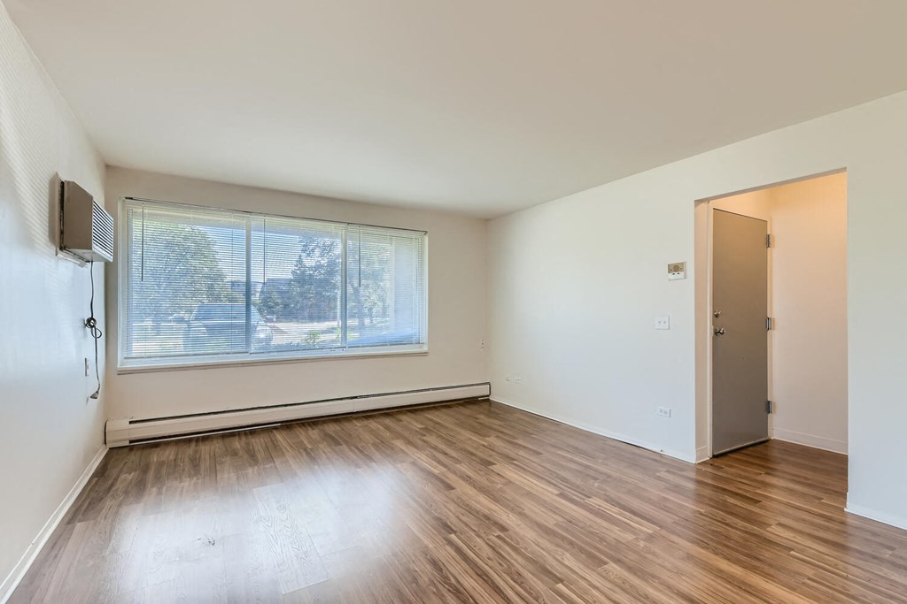 an empty living room with a large window and wood floors