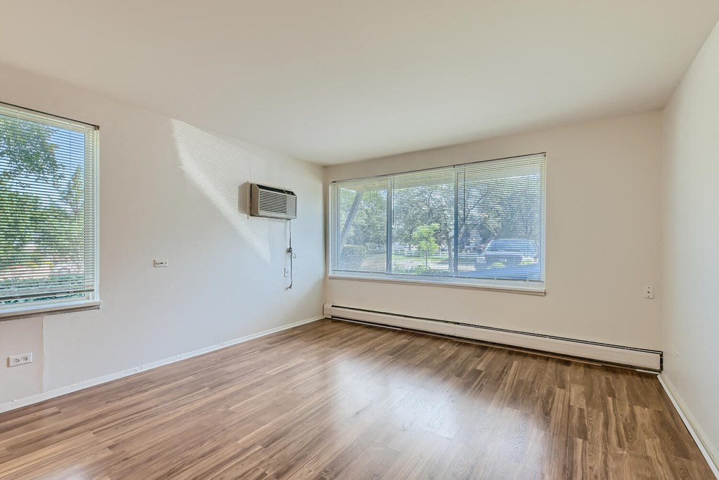 an empty living room with wood floors and a large window