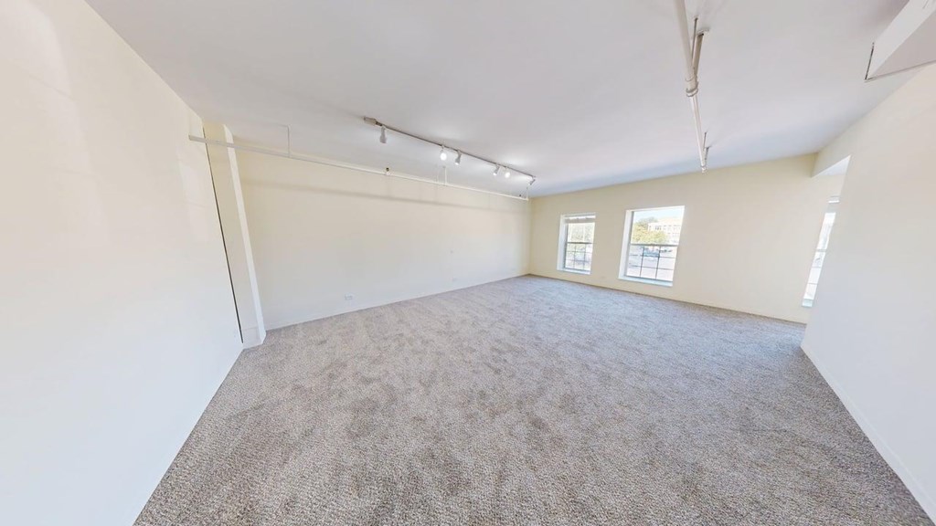 A large, living room with carpeted floor and white walls.