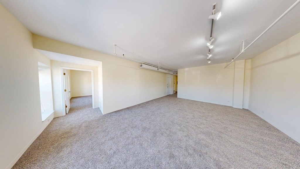 A large, empty room with carpeted flooring and white walls.