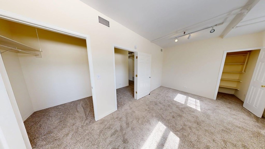 A spacious room with carpeted floor and white walls.