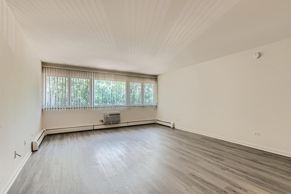 the living room of a house with wood floors and a large window