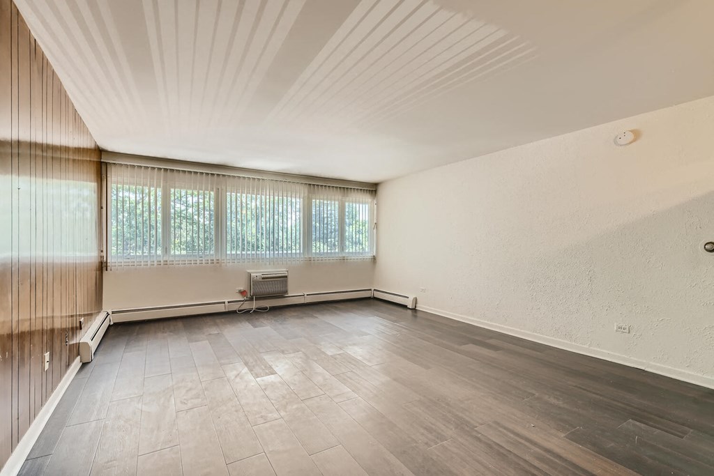 an empty living room with wood floors and a large window
