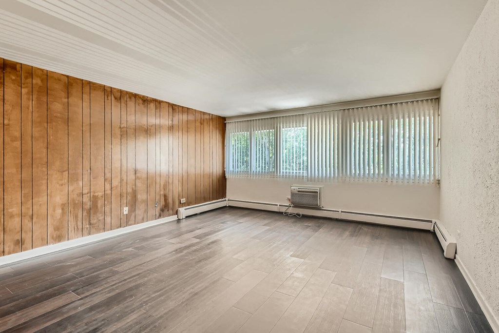 an empty living room with wood flooring and a large window