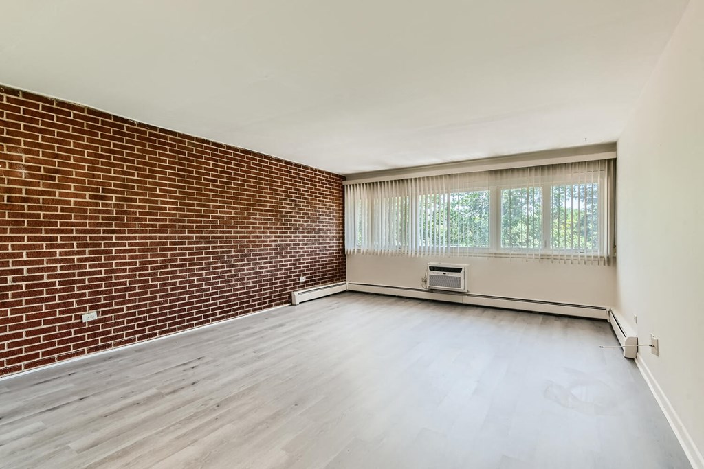 an empty living room with a brick wall and a window
