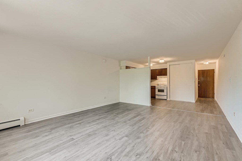 the living room and kitchen of an empty house with wood flooring