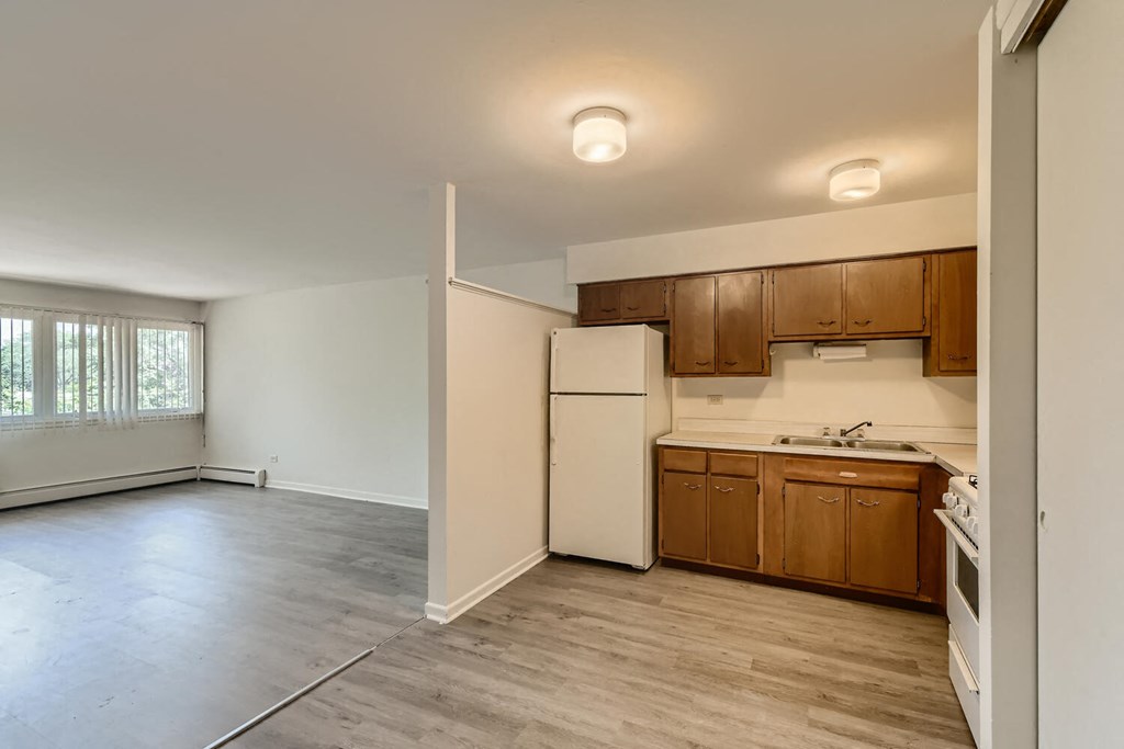 an empty kitchen with white appliances and wooden cabinets