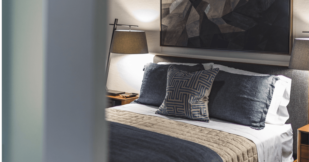 a bedroom with a bed with pillows and a painting on the wall