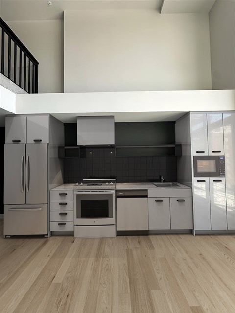 A modern kitchen with wooden floors and stainless steel appliances.