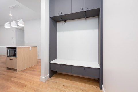 A kitchen with a white wall and a grey bench.