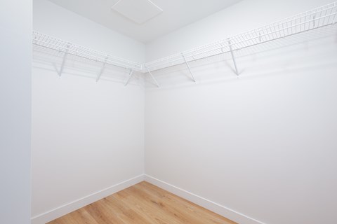 A white wall with a wooden floor and a white shelf.