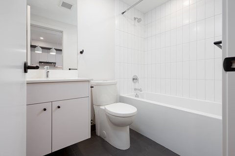 A white toilet sits in a bathroom with white tiles.
