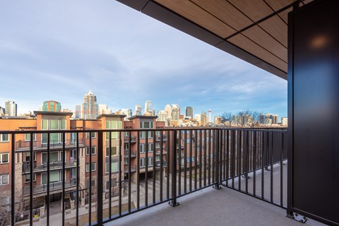 A balcony with a metal railing overlooks a city skyline.