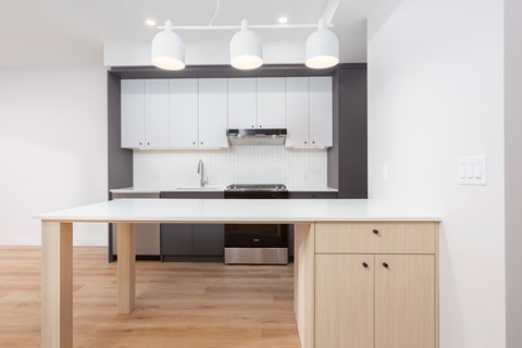 A modern kitchen with a wooden table and white cabinets.