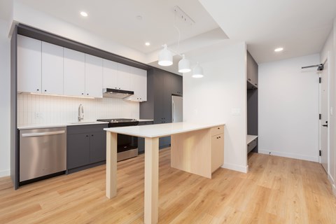 A modern kitchen with a wooden table and stainless steel appliances.