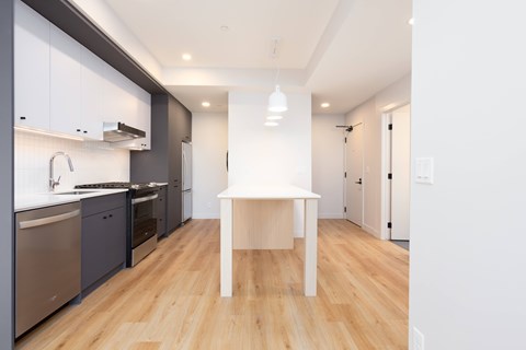 A modern kitchen with a white table and wooden floors.