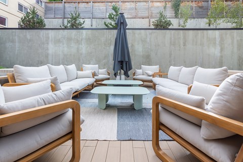 A patio with white couches and a blue umbrella.