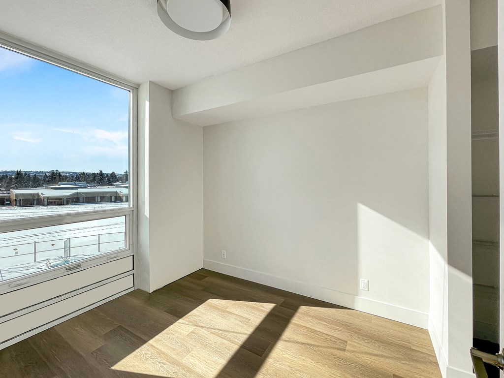 an empty living room with a large window and wood flooring