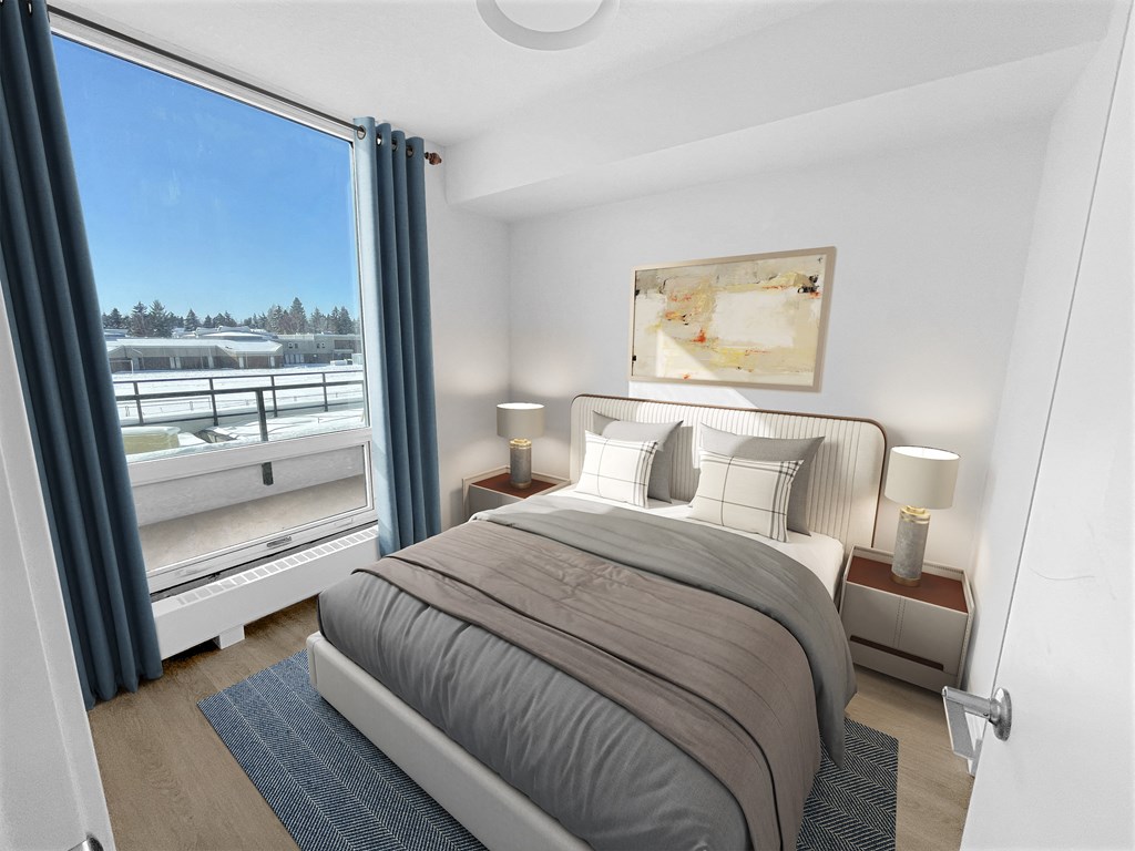 a bedroom with a large window and a bed with a comforter