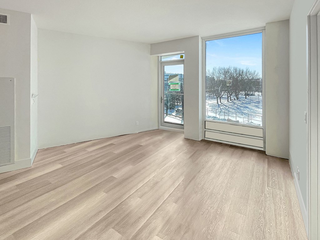 an empty living room with a large window and wood flooring