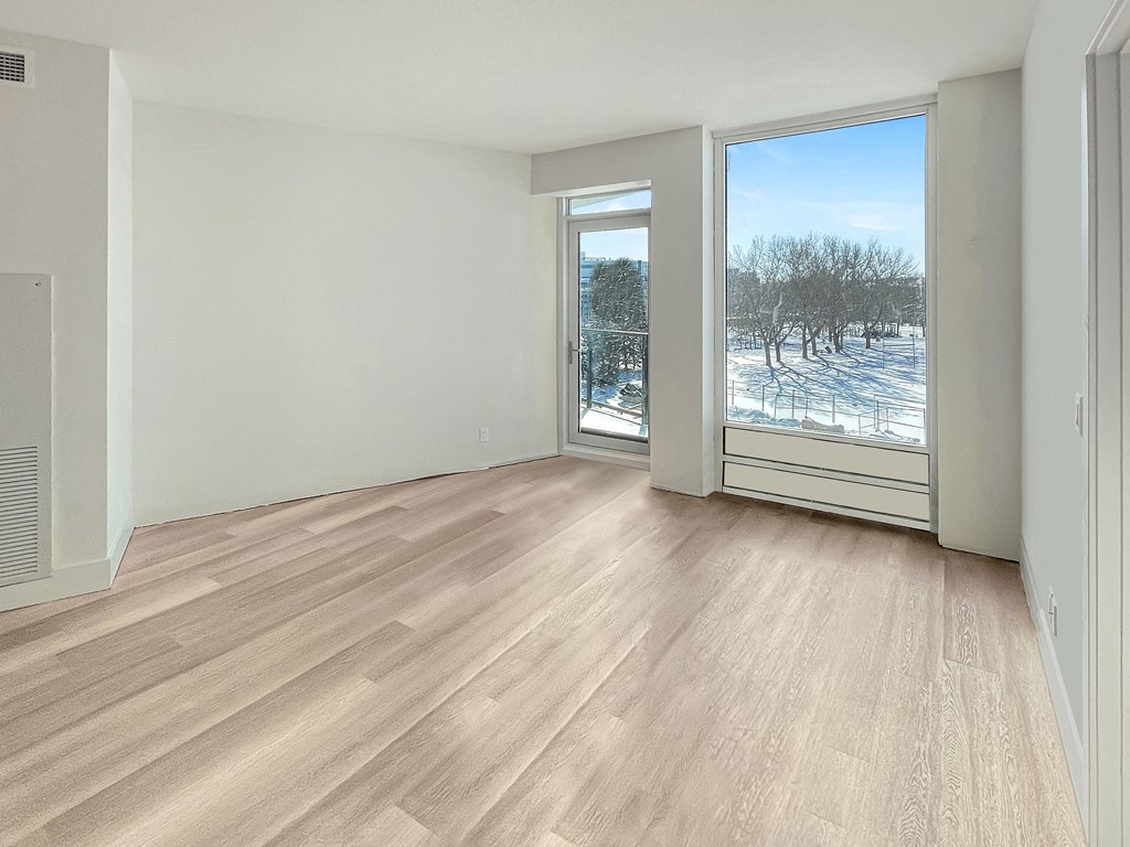 an empty living room with a large window and wood flooring