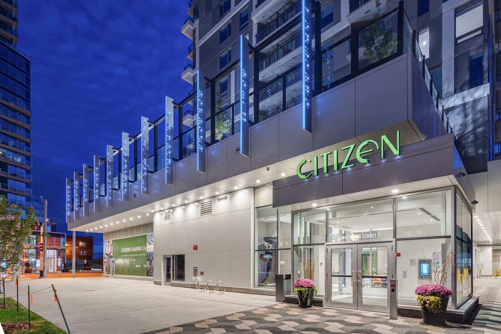 a hotel facade with a sidewalk in front of it at night