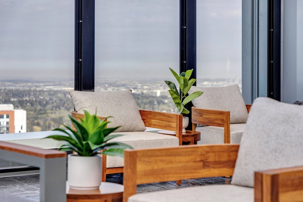 Living room with chairs and plants and a view of the city at Citizen on Jasper, Alberta, T5K 0M5