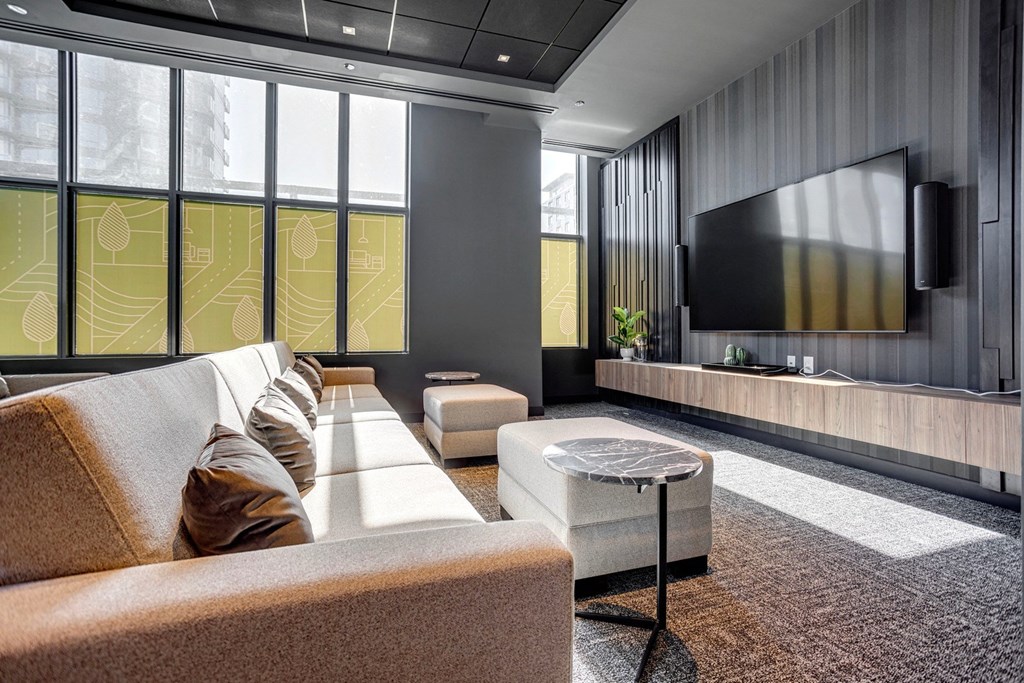 a living room with a couch and coffee table in front of a wall of windows  at Citizen on Jasper, Alberta, T5K 0M5