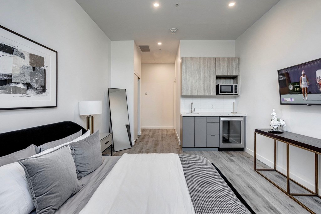a bedroom with a large bed and a kitchen in the background  at Citizen on Jasper, Edmonton