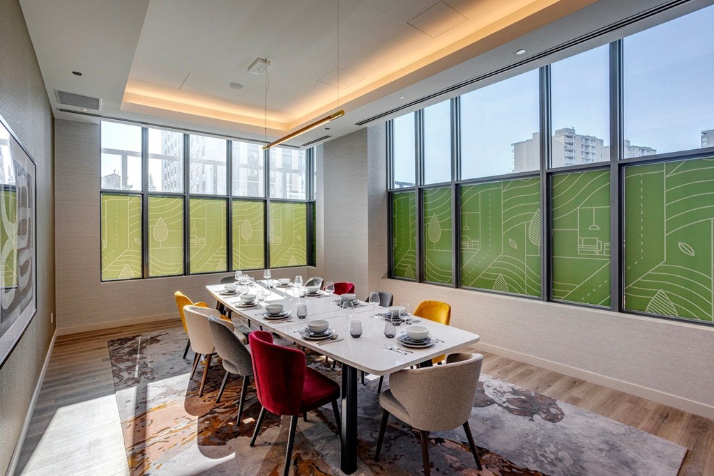 a dining room with a long white table and yellow and red chairs  at Citizen on Jasper, Edmonton, AB