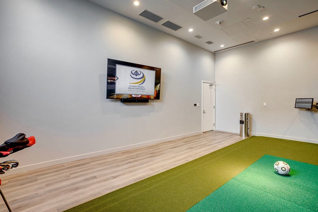 a recreation room with a soccer ball on the floor and a tv on the wall  at Citizen on Jasper, Edmonton, AB