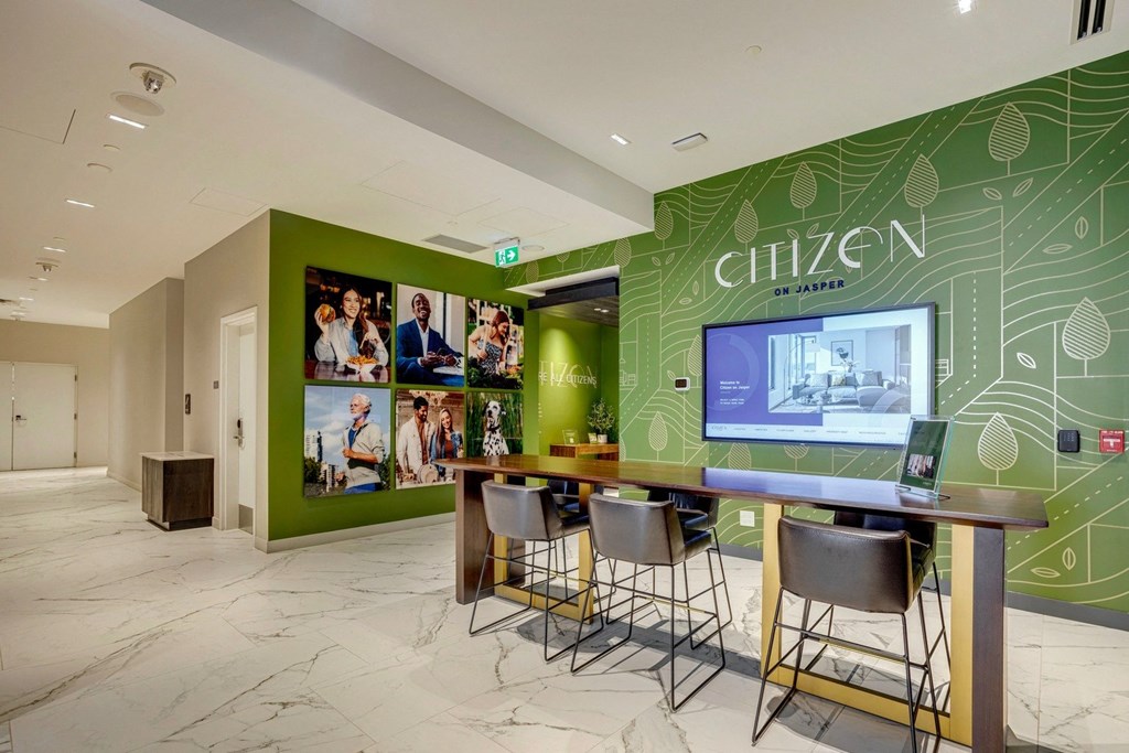a room with a table and chairs in front of a green wall with pictures on it  at Citizen on Jasper, Edmonton, Alberta
