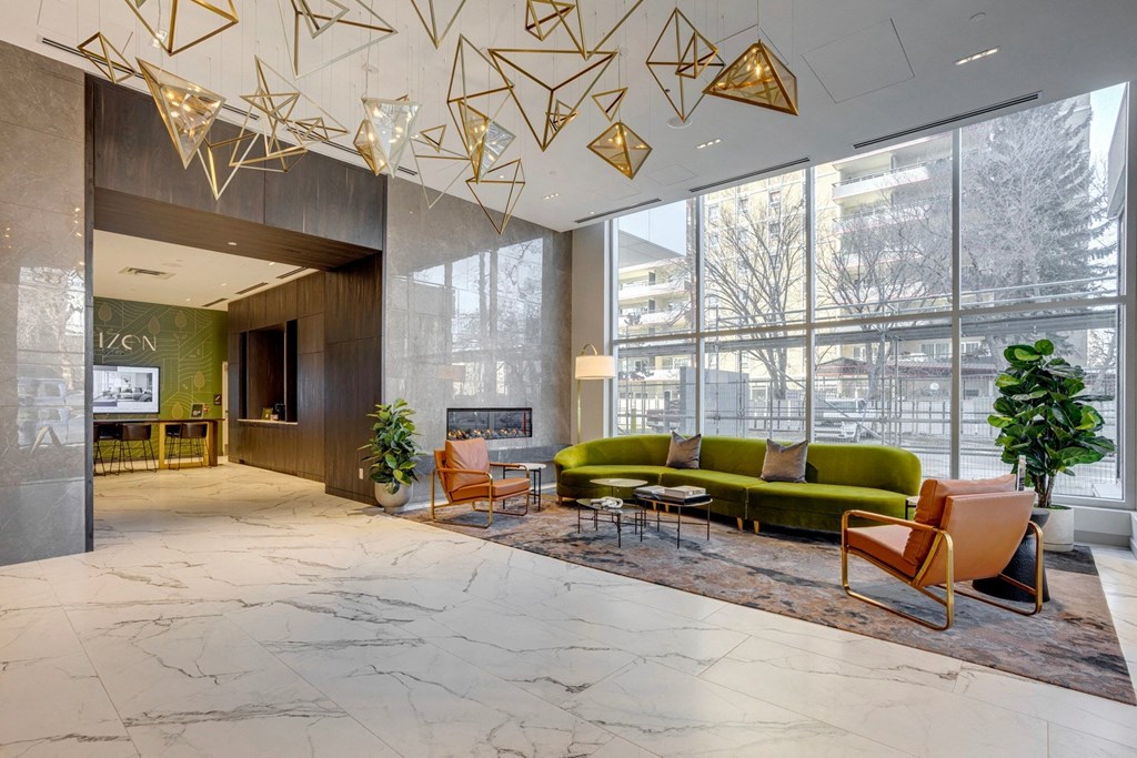 a large lobby with a green couch and orange chairs  at Citizen on Jasper, Edmonton, AB, T5K 0M5
